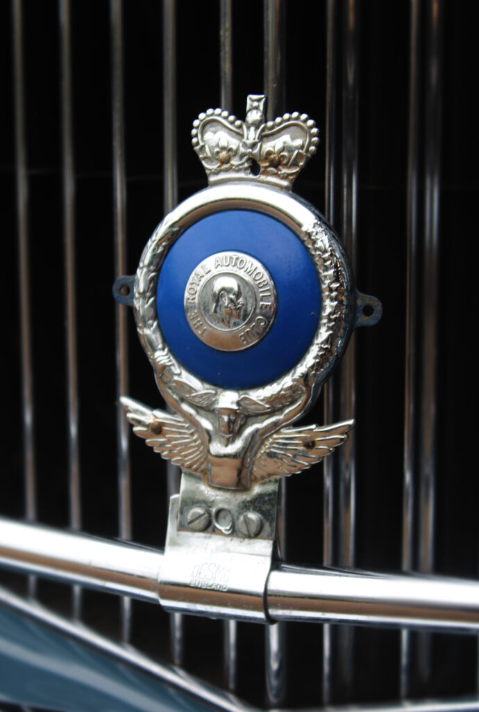 Vintage badge for the Royal Automobile Club. The badge is round with a royal blue centre and attached to the vehicle's grill.