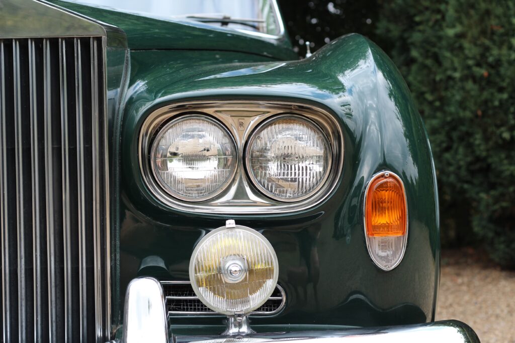 close up of headlight details on left hand side of rolls royce silver cloud III. The car is green