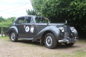 Rolls royce silver dawn rally car, 3/4 profile. Car is silver/grey with rally stickers on the side