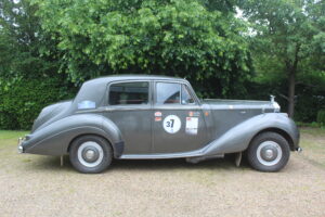 Rolls royce silver dawn rally car, drivers side profile. Car is silver/grey with rally stickers on the side