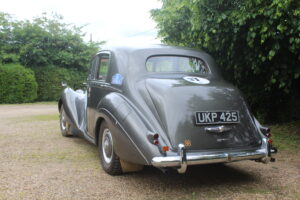 Rolls royce silver dawn rally car, 3/4 profile. Car is silver/grey with rally stickers on the side