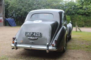 Rolls royce silver dawn rally car, 3/4 profile. Car is silver/grey with rally stickers on the side