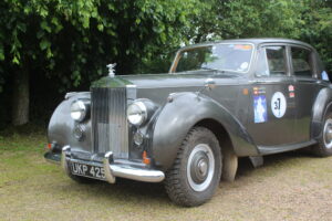 Rolls royce silver dawn rally car, 3/4 profile. Car is silver/grey with rally stickers on the side