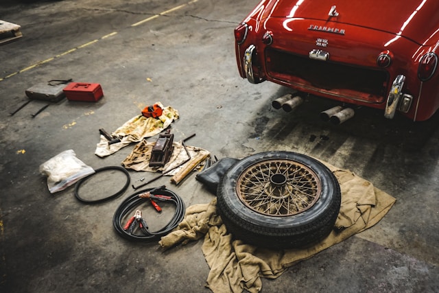 emergency items to keep in car, laid out on floor behind red classic car