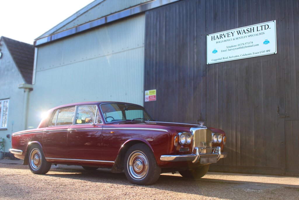 Red Bentley T1 parked showing three quarters view. The grill and headlights are visible.
