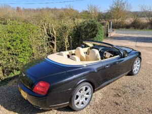 Bentley GT in black with roof down, drivers side view