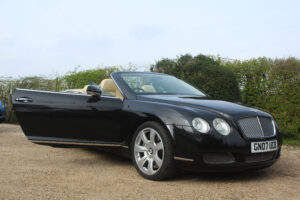 Bentley GT in black with roof down, drivers side view with door open