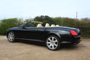 Bentley GT in black with roof down, passenger side view