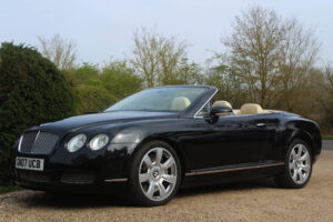 Bentley GT in black with roof down, passenger side view