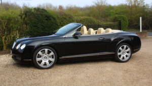 Bentley GT in black with roof down, passenger side view