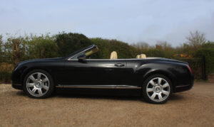 Bentley GT in black with roof down, passenger side view