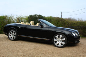 Bentley GT in black with roof down, drivers side view