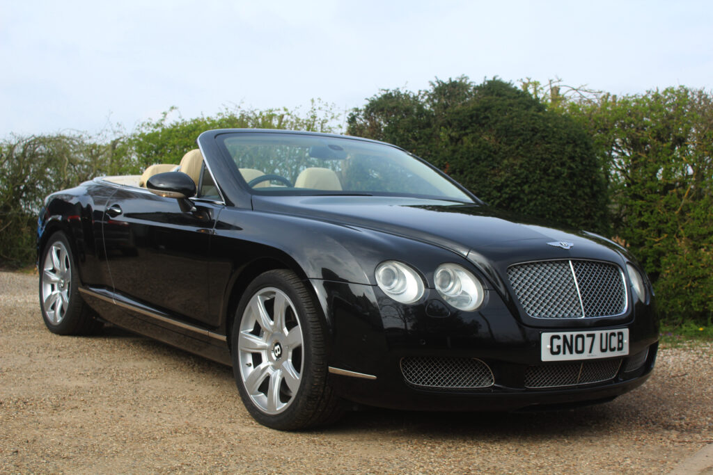 Bentley GT in black with roof down, drivers side view