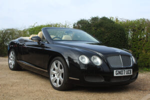 Bentley GT in black with roof down, drivers side view