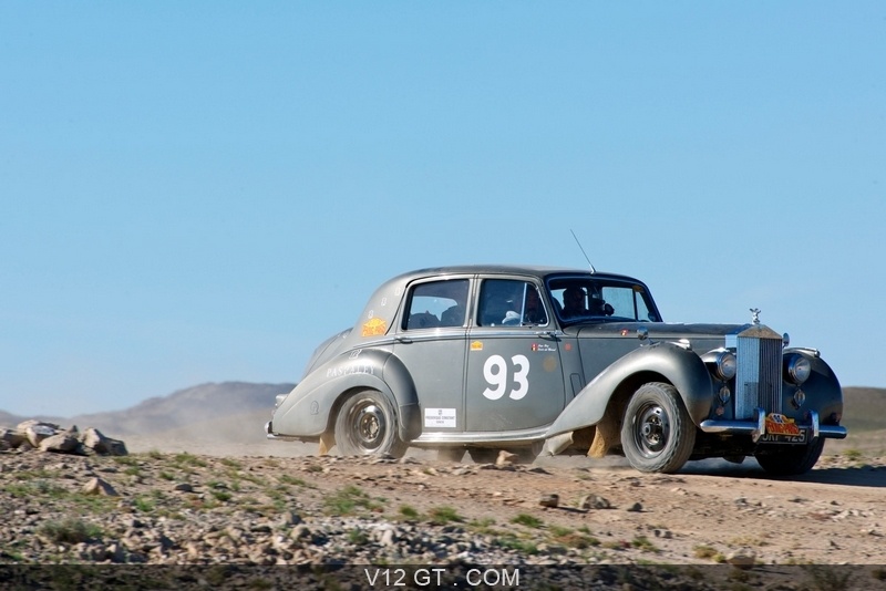 Rolls Royce silver Dawn rally car in gun metal colour, driving across the dusty terrain on the Peking to Paris Rally