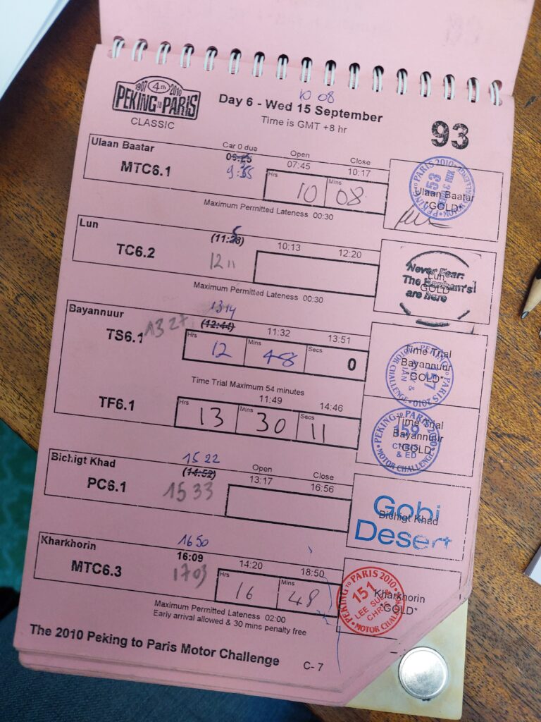 Peking to Paris rally log book for day 6 of the Peking to Paris Rally. Log book is pink with stamps and hand written times on it