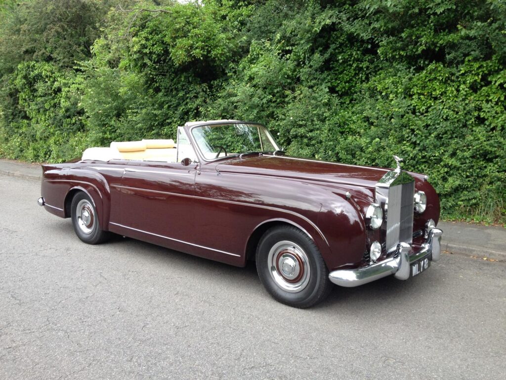 Rolls royce silver cloud drophead coupe in deep red with a cream interior and hood down