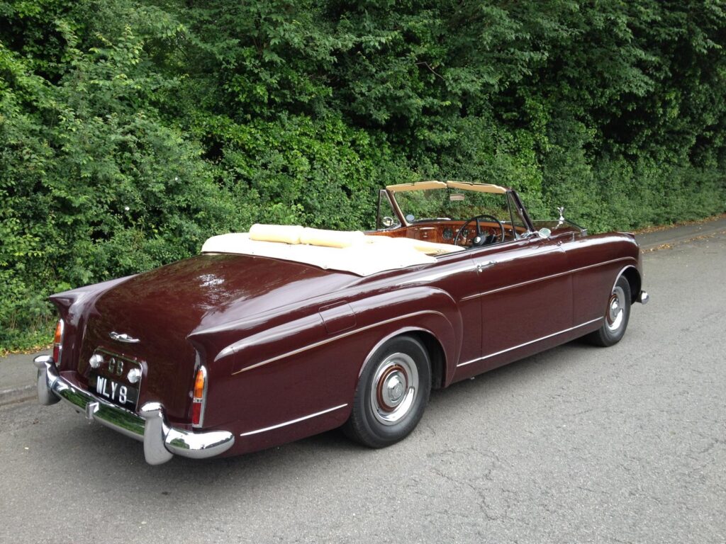 Rolls royce silver cloud drophead coupe in deep red with a cream interior and hood down